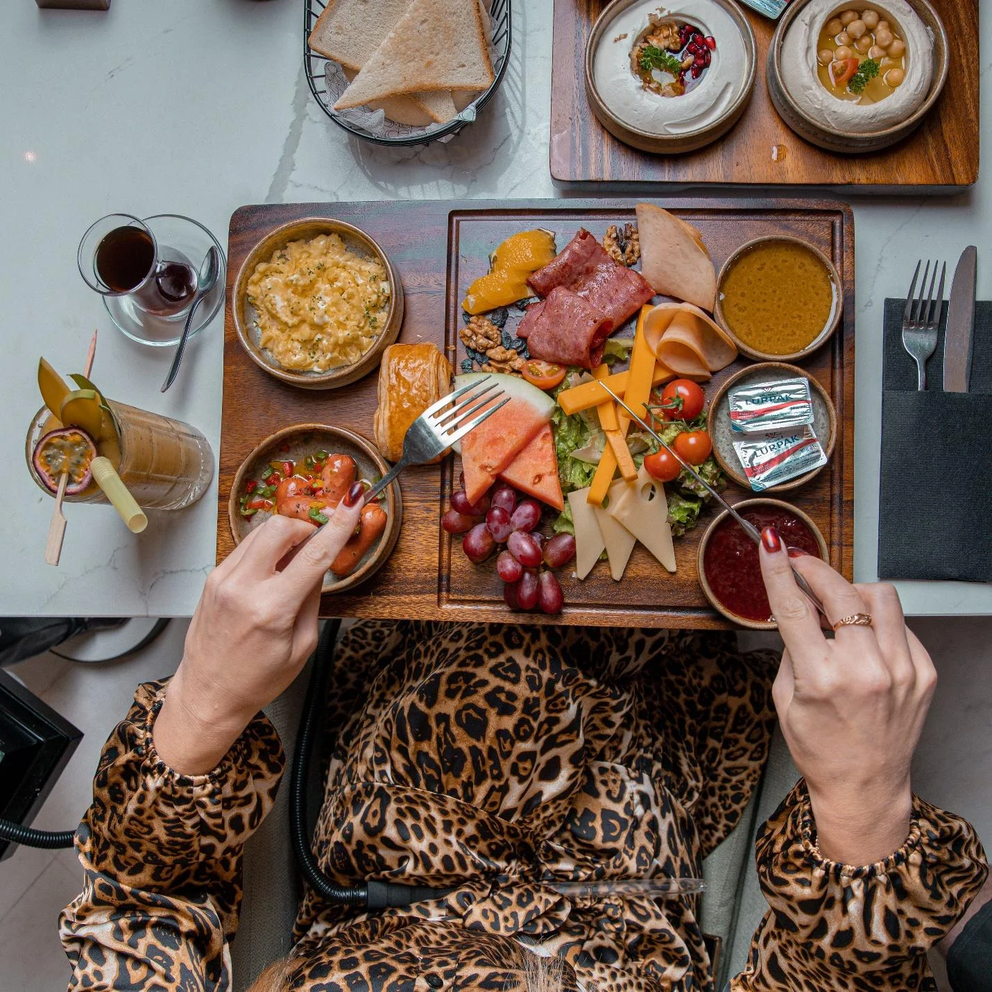 A woman with fork and knife in both hands over a platter