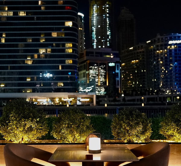 Scenic waterfront outdoor terrace seating at Babati Restaurant Dubai at night.