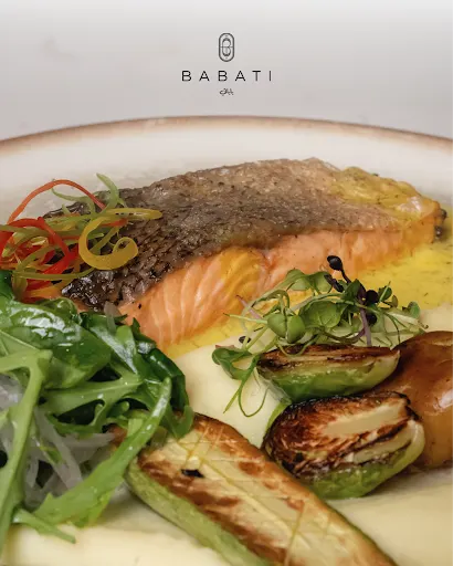 Crispy skin salmon fillet on creamy mash with charred Brussels sprouts, grilled zucchini, and fresh greens at Babati