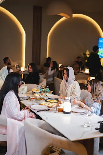 Friends sharing a Levantine spread with baked eggs, fresh bread, dips, and tea in Babati's warmly lit arched dining room