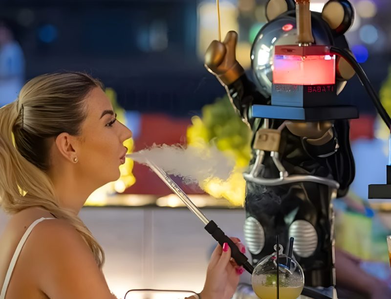 Woman with ponytail uses bear-shaped hookah with glowing BABATI logo.